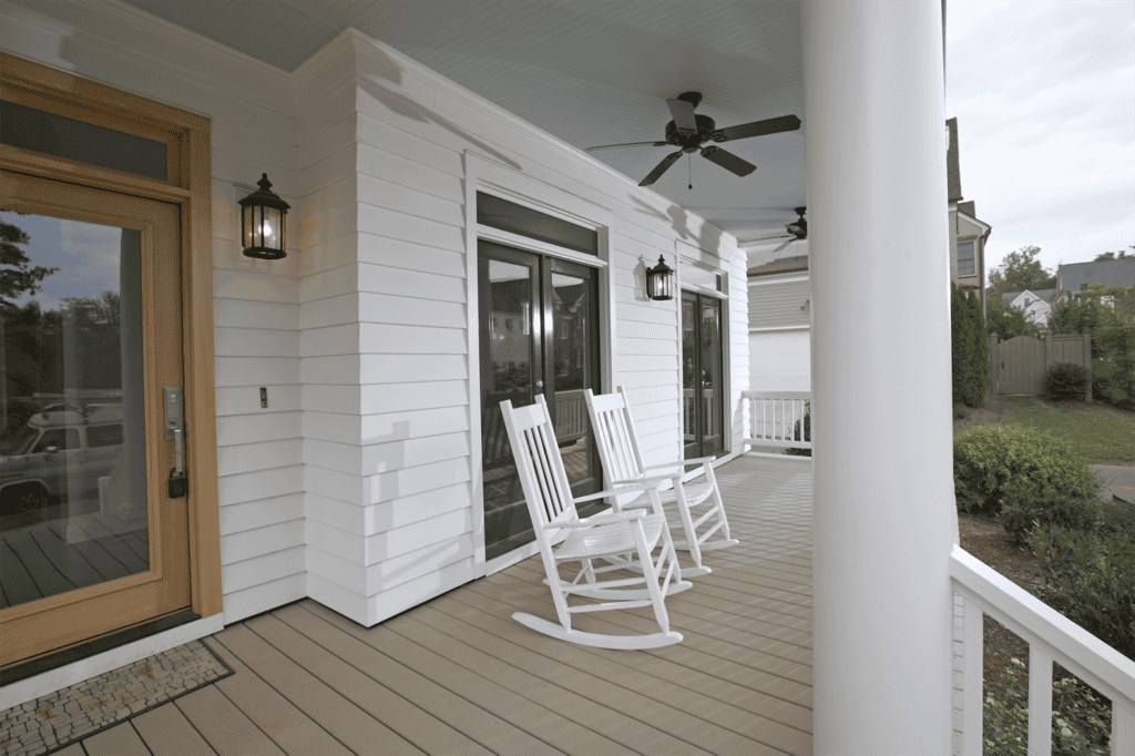 A porch with two white rocking chairs, a ceiling fan, hanging lanterns, and sliding glass doors from Relief Windows in Baton Rouge.