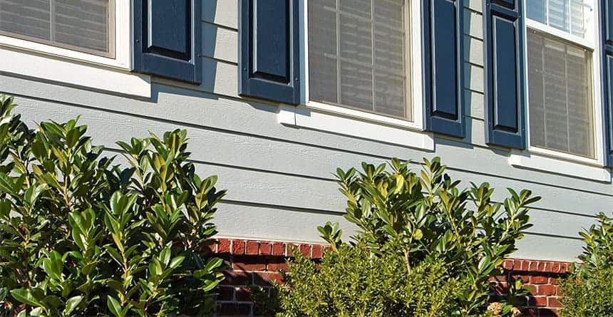 Close up of home with brick foundation and light blue siding