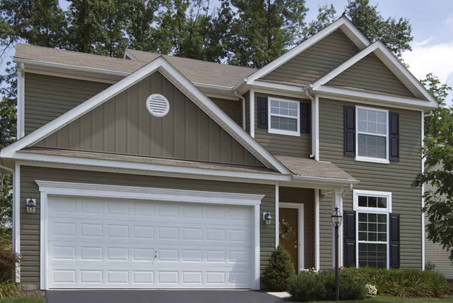 Two-story home with white garage and khaki colored siding