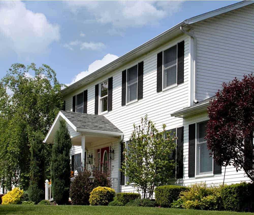 Two story home with white siding, black shutters, and covered front porch door