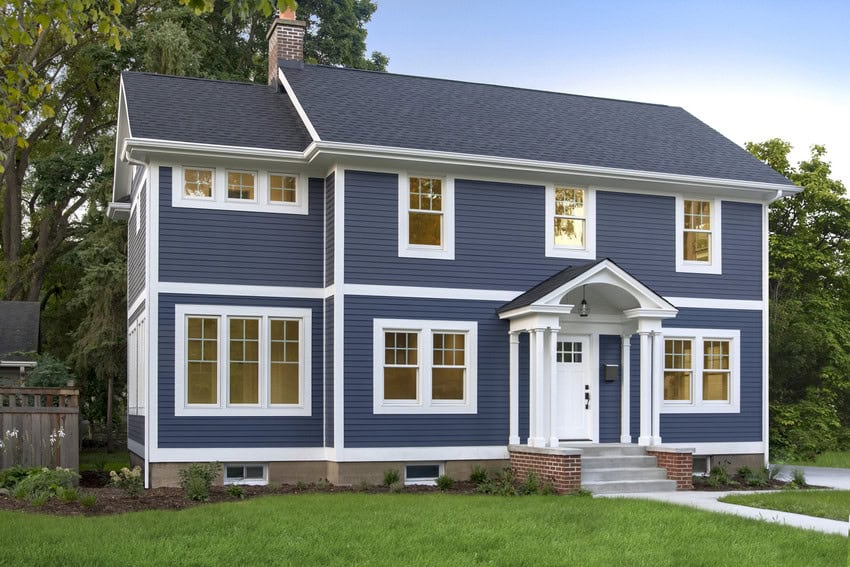 Story story home with navy blue siding, white front porch columns, and white windows