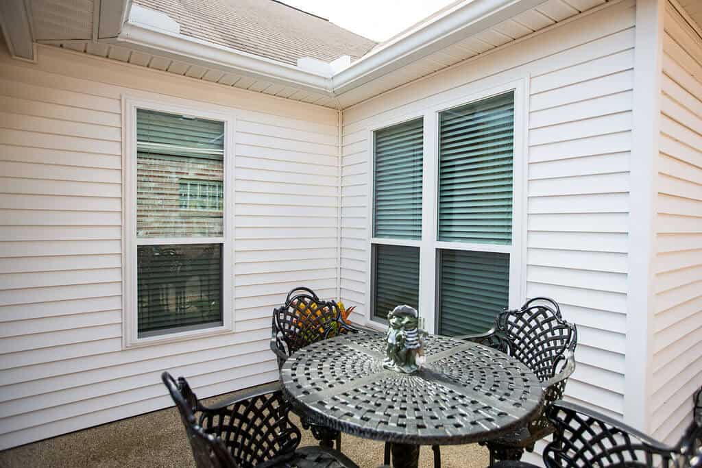 Angled view of a back porch with white vinyl siding