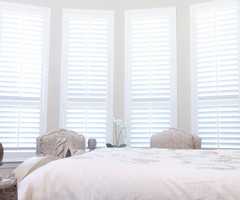 Bright bedroom windows with custom white interior shutters