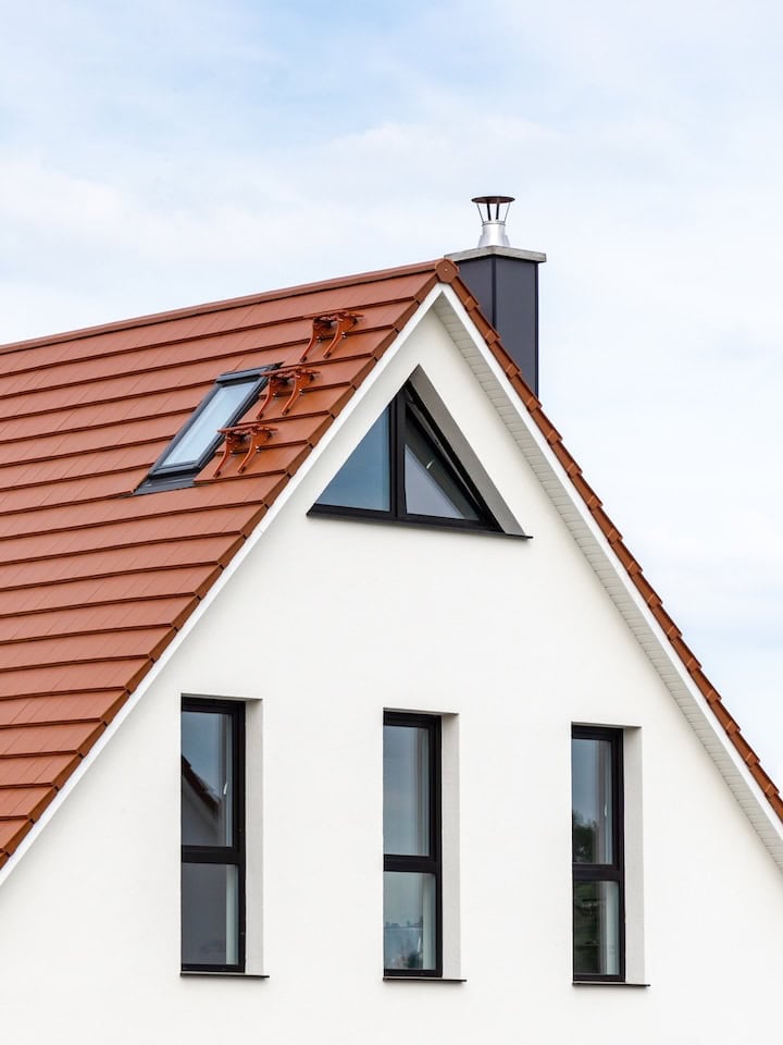 Trangle window on a white house with terracotta-colored roof