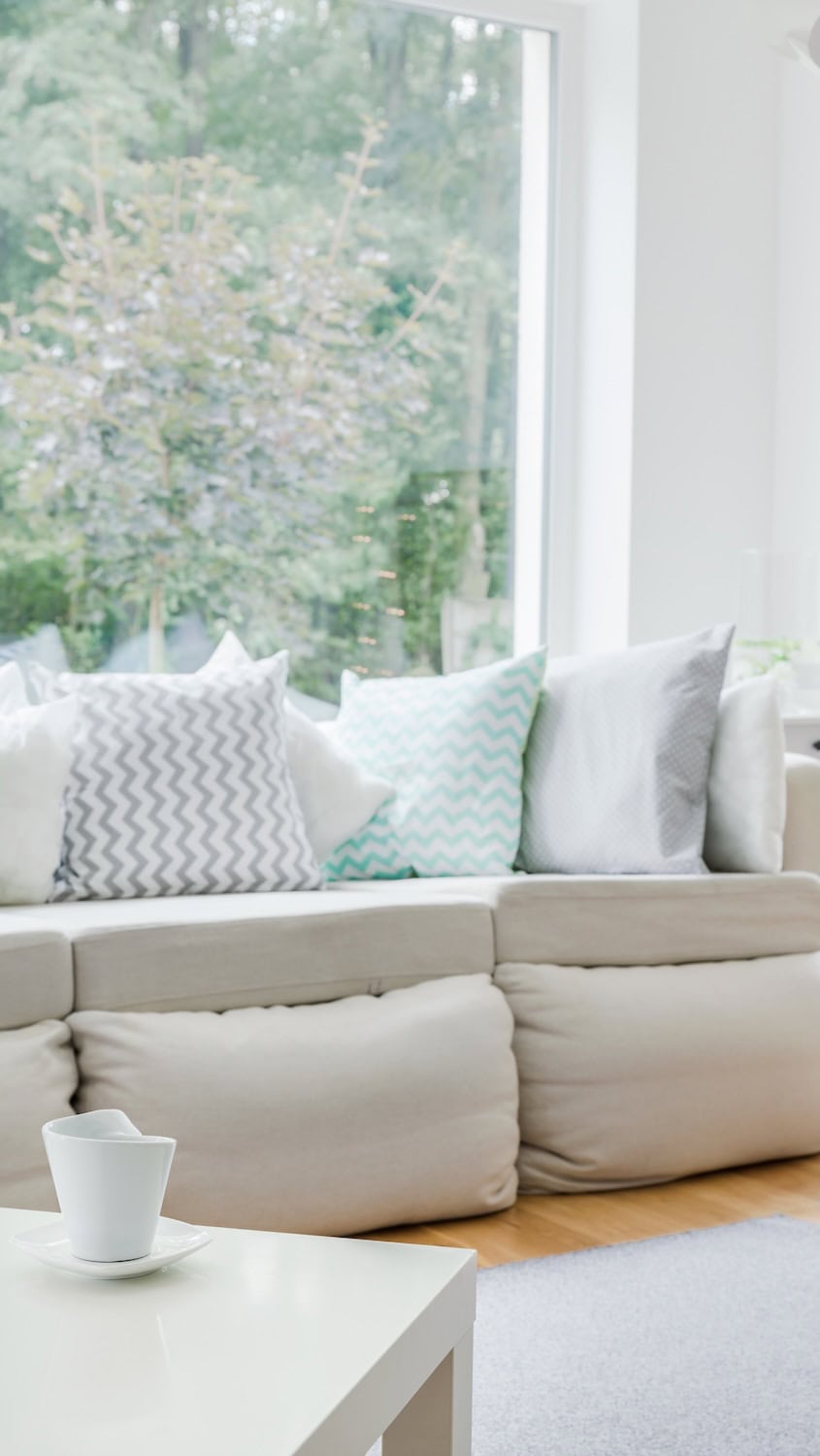 White sofa with cushions in front of large picture window