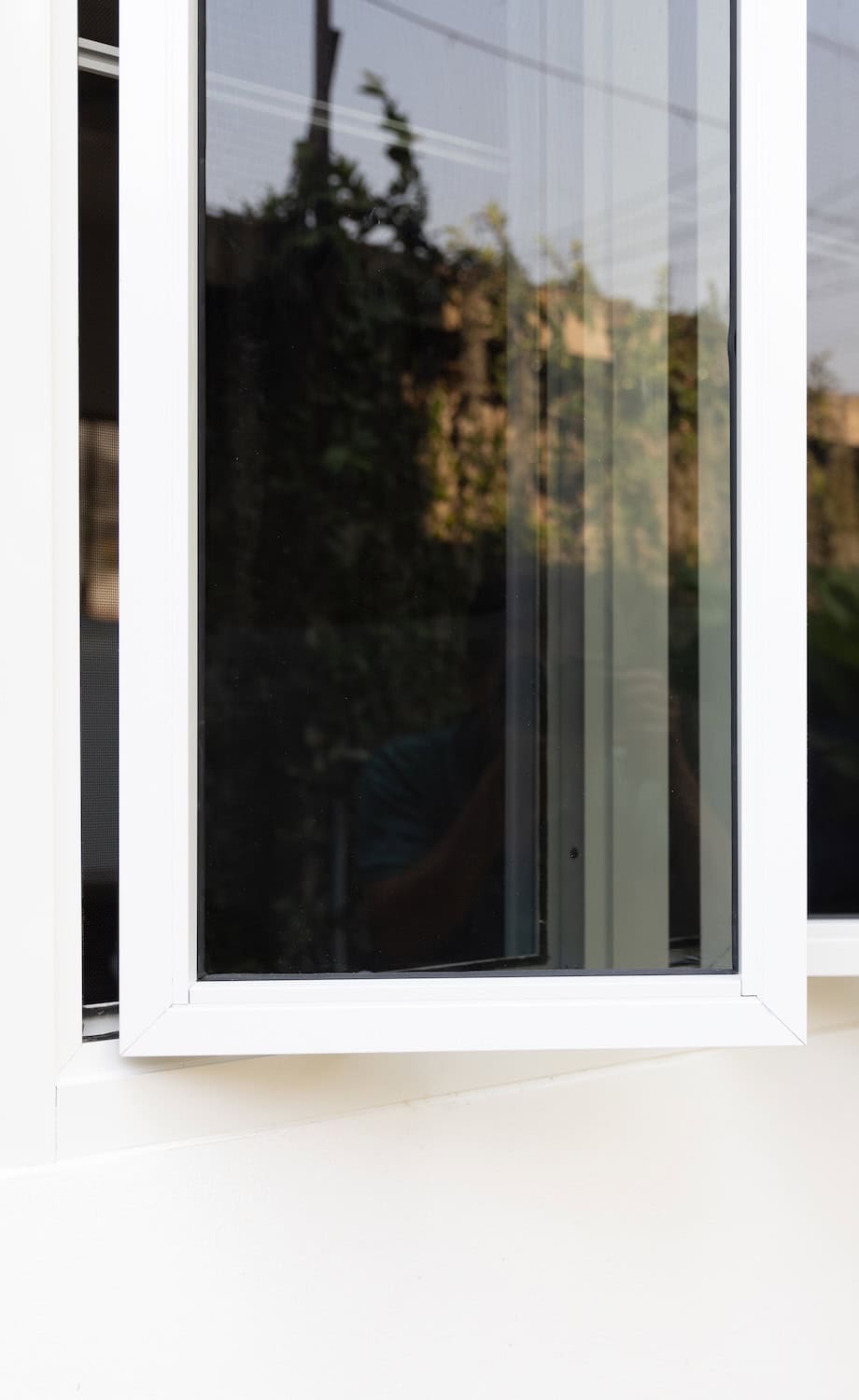 Three panel aluminium casement window on white wall.