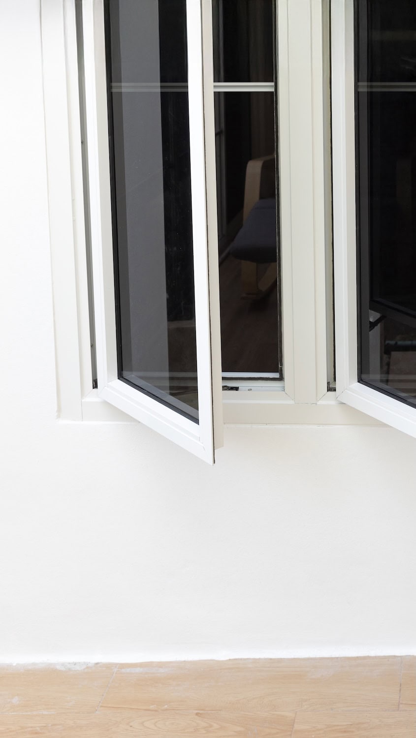 Open three-panel aluminium casement windows on white wall.